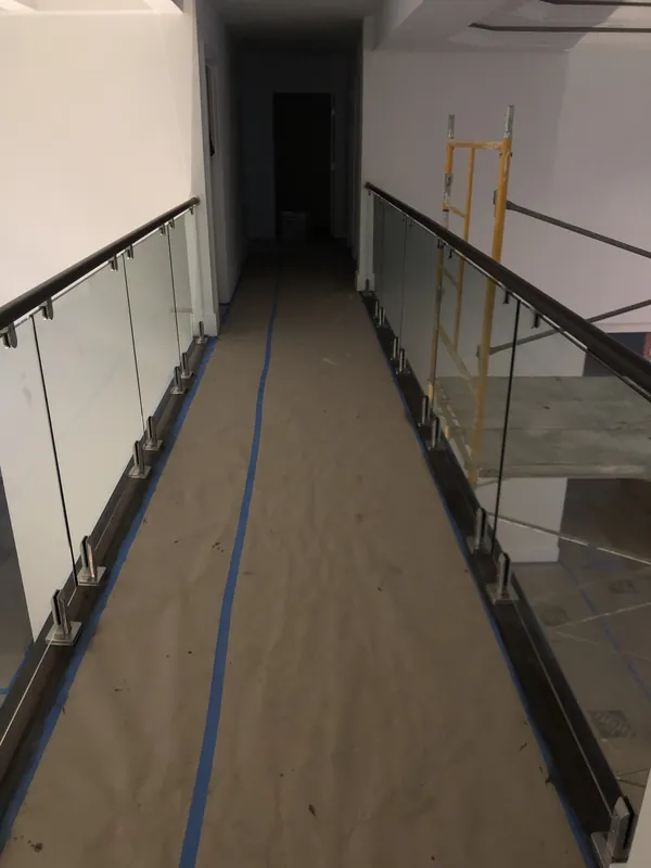 Glass panels and dark handrails along an interior upper-floor walkway