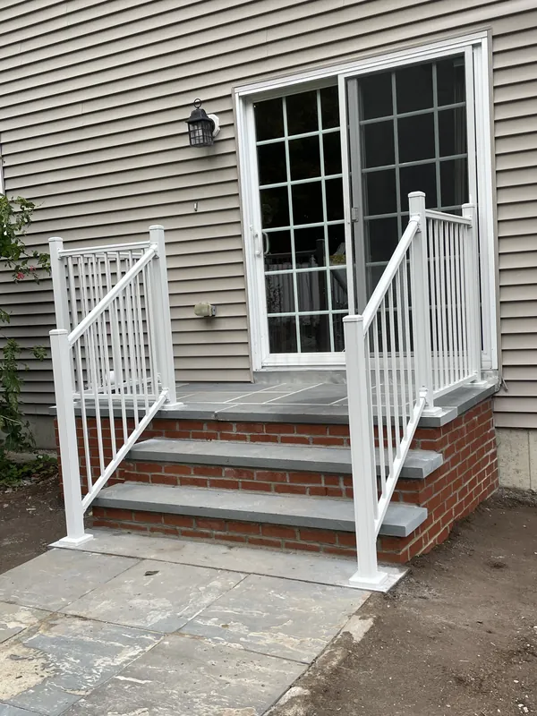 White vertical-baluster railings on both sides of brick entry steps